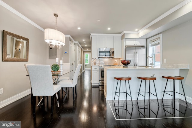 418 Seward Sq SE Unit 3, Washington, DC 20003 - kitchen featuring stainless steel appliances, a peninsula, a sink, ornamental molding, and a kitchen bar