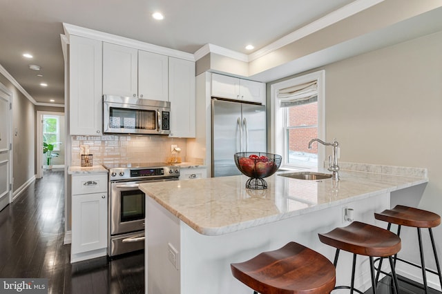 418 Seward Sq SE Unit 3, Washington, DC 20003 - kitchen with appliances with stainless steel finishes, a sink, crown molding, light stone counters, and white cabinetry