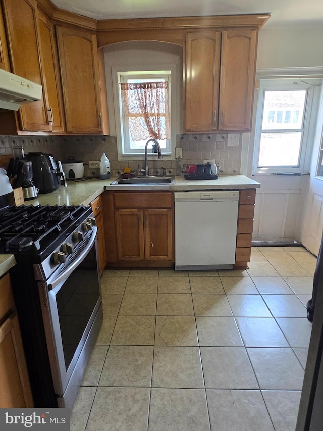 kitchen with backsplash, stainless steel gas range oven, dishwasher, a sink, and light countertops