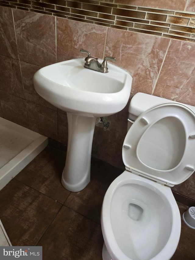 bathroom featuring tile walls, toilet, and a shower stall