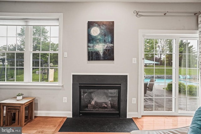 living area featuring wood finished floors, baseboards, and a fireplace with flush hearth