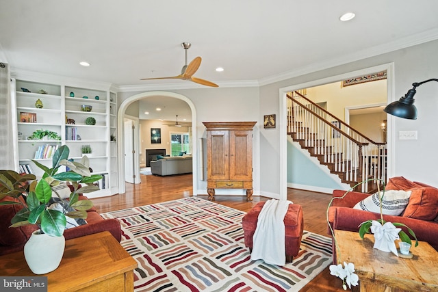 living room featuring a ceiling fan, ornamental molding, recessed lighting, and stairway