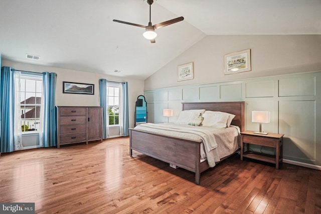bedroom featuring a ceiling fan, high vaulted ceiling, visible vents, and wood finished floors