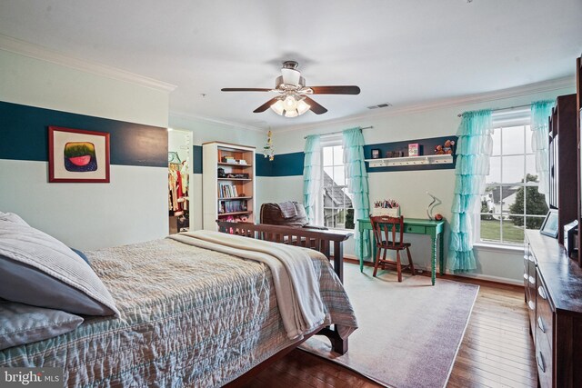 bedroom with ornamental molding, hardwood / wood-style flooring, ceiling fan, and visible vents
