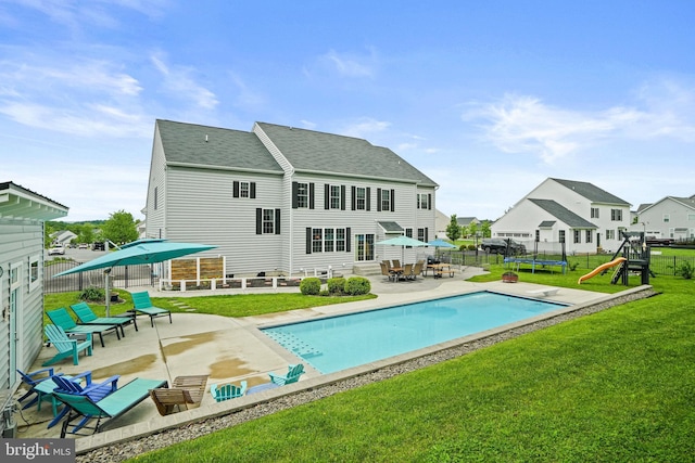 back of property featuring a trampoline, a yard, a patio, a playground, and a shingled roof