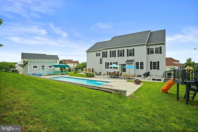 rear view of property featuring a patio, a lawn, a fenced in pool, and an outbuilding