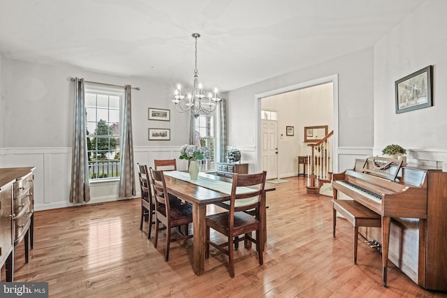 dining space with a notable chandelier, a decorative wall, a wainscoted wall, and light wood-style floors
