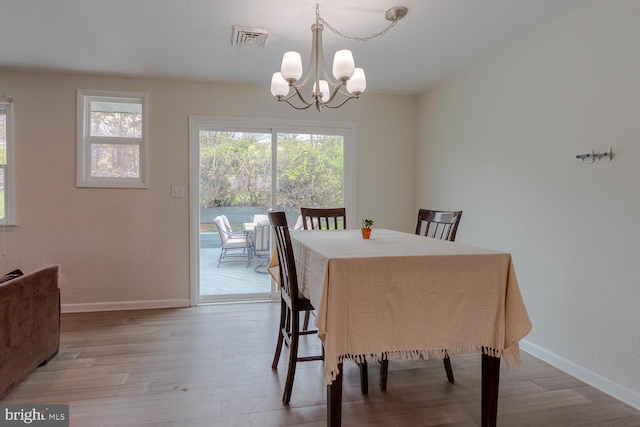 dining space with baseboards, light wood-style flooring, a chandelier, and visible vents