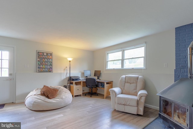 living area featuring baseboards, a wood stove, and wood finished floors