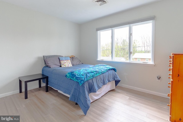 bedroom featuring baseboards, visible vents, and wood finished floors