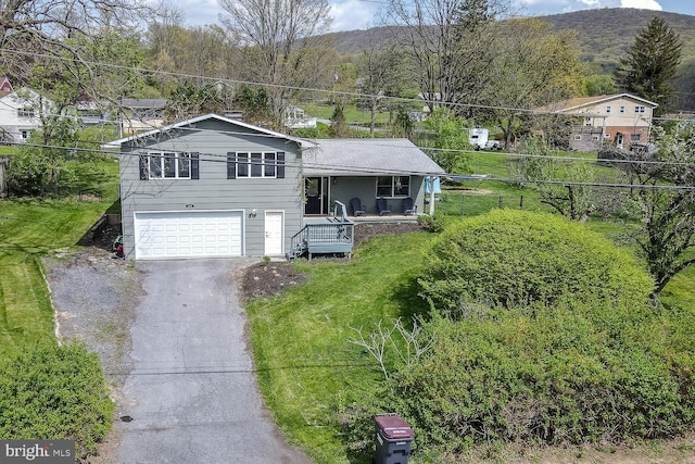 split level home with covered porch, driveway, a front yard, a garage, and a mountain view