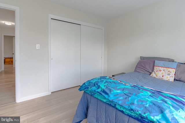 bedroom with baseboards, light wood-style flooring, and a closet