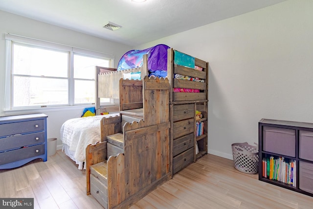 bedroom featuring baseboards, wood finished floors, and visible vents