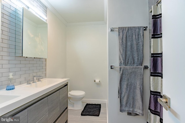 full bath with a sink, toilet, baseboards, decorative backsplash, and ornamental molding