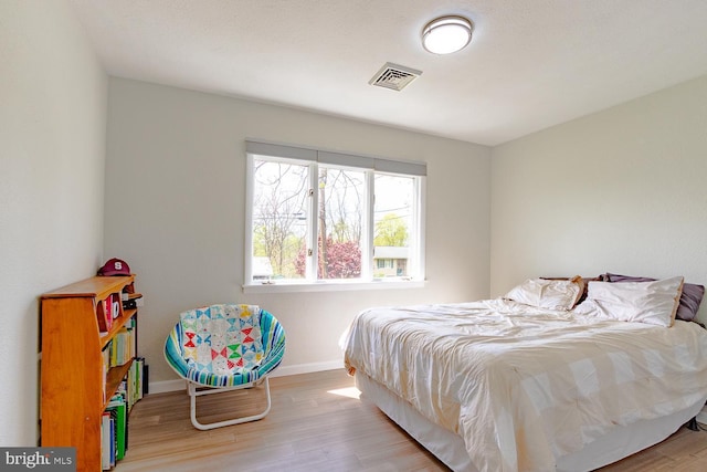 bedroom with baseboards, visible vents, and wood finished floors