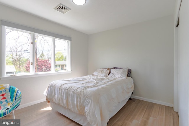 bedroom featuring baseboards, visible vents, and wood finished floors