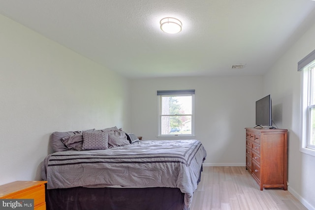 bedroom featuring baseboards, light wood finished floors, and visible vents
