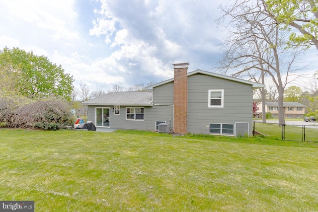 rear view of property featuring a yard, central AC, fence, and a chimney