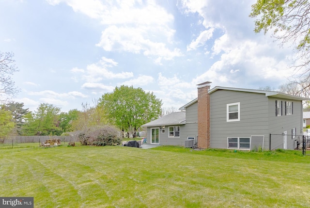 back of property featuring a yard, fence, a chimney, and central air condition unit