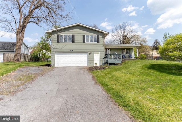 split level home with an attached garage, driveway, a front yard, and a porch