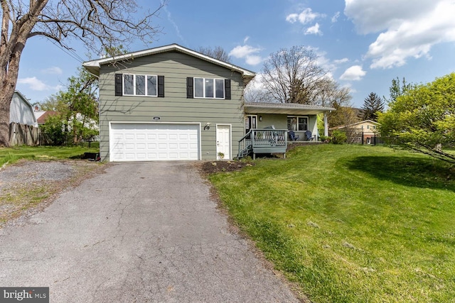 split level home featuring a garage, aphalt driveway, fence, a front yard, and a porch