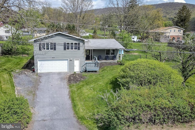 split level home featuring an attached garage, a front lawn, aphalt driveway, a porch, and a mountain view
