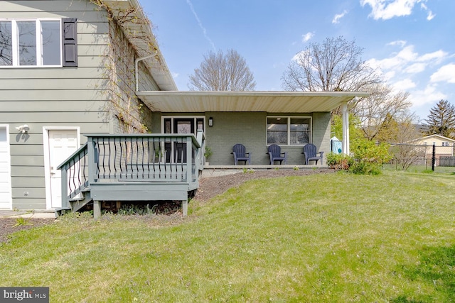 rear view of house with a lawn, brick siding, fence, and a deck