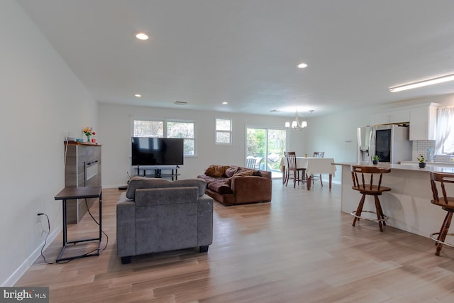 living area with light wood-style floors, baseboards, recessed lighting, and a chandelier