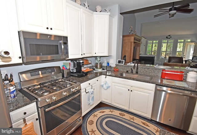 kitchen with a ceiling fan, a sink, open floor plan, white cabinets, and appliances with stainless steel finishes