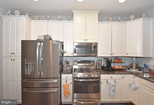 kitchen featuring stainless steel appliances, white cabinets, and dark stone countertops
