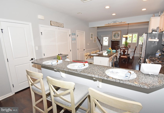 kitchen featuring freestanding refrigerator, dark wood finished floors, recessed lighting, a kitchen bar, and a center island
