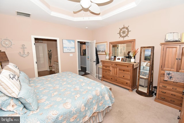 bedroom featuring a ceiling fan, a tray ceiling, ornamental molding, visible vents, and light carpet