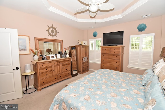 bedroom with carpet flooring, a tray ceiling, crown molding, visible vents, and ceiling fan