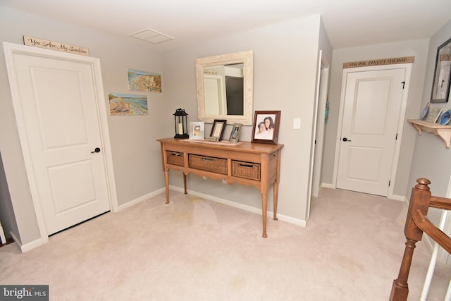 corridor with baseboards, visible vents, and light colored carpet