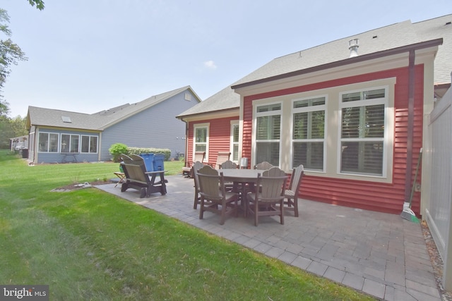 rear view of property with roof with shingles, a patio area, and a lawn