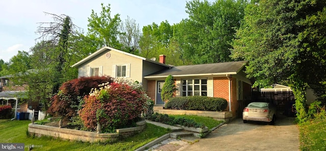 split level home with fence, a chimney, and concrete driveway