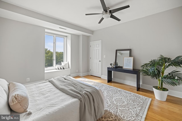 bedroom featuring a ceiling fan, baseboards, visible vents, and wood finished floors