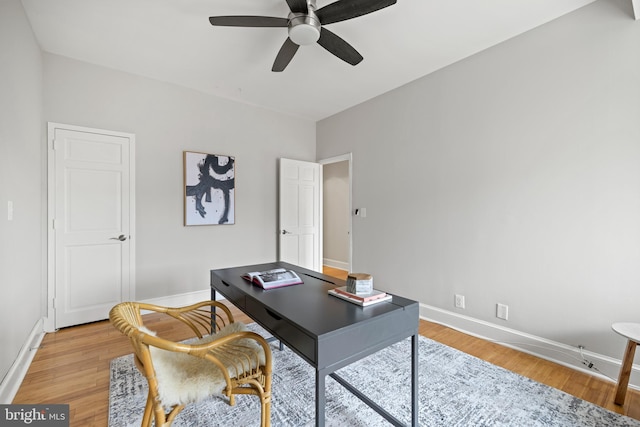 office space with baseboards, a ceiling fan, and light wood finished floors