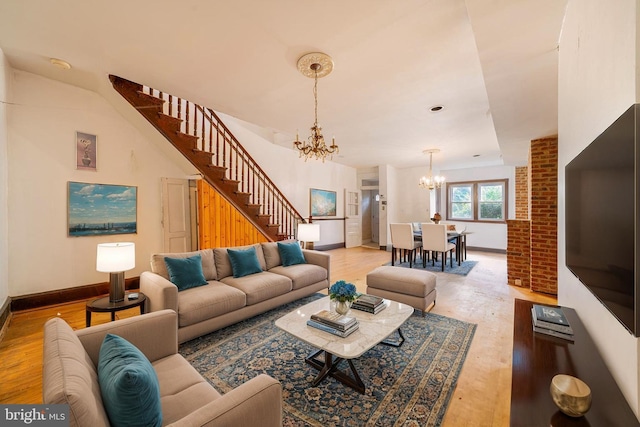 living room with a chandelier, stairs, light wood finished floors, and baseboards