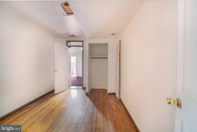 unfurnished bedroom with hardwood / wood-style flooring, a closet, and baseboards