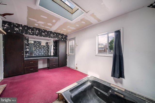 misc room with a skylight and dark colored carpet