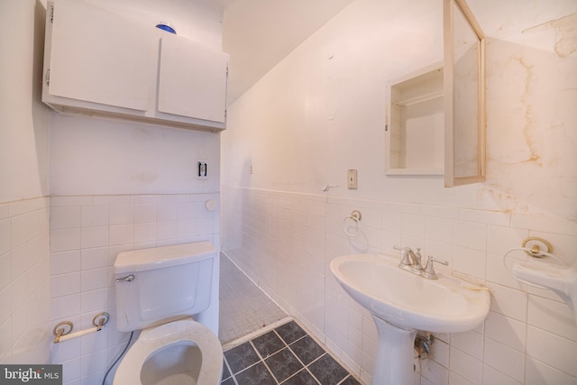 bathroom featuring tile walls, toilet, wainscoting, and tile patterned floors