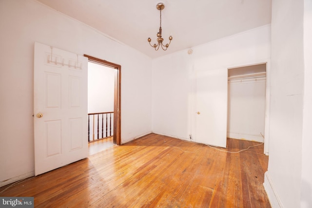 unfurnished bedroom with light wood-style flooring, a chandelier, and a closet