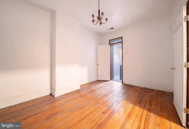 unfurnished bedroom featuring hardwood / wood-style floors and a chandelier