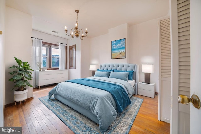 bedroom with light wood finished floors and a chandelier
