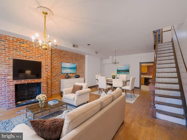 living room with a chandelier, stairs, hardwood / wood-style flooring, and a fireplace
