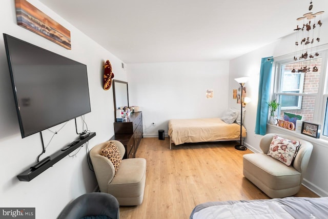 bedroom featuring baseboards, light wood finished floors, and visible vents