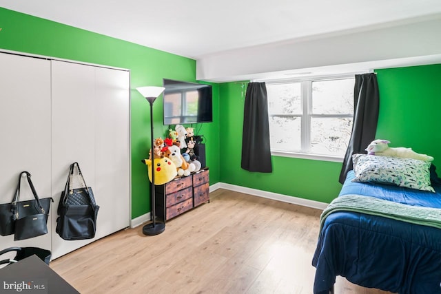 bedroom with baseboards, wood finished floors, and a closet