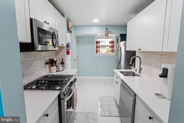 kitchen featuring a sink, appliances with stainless steel finishes, backsplash, and light countertops