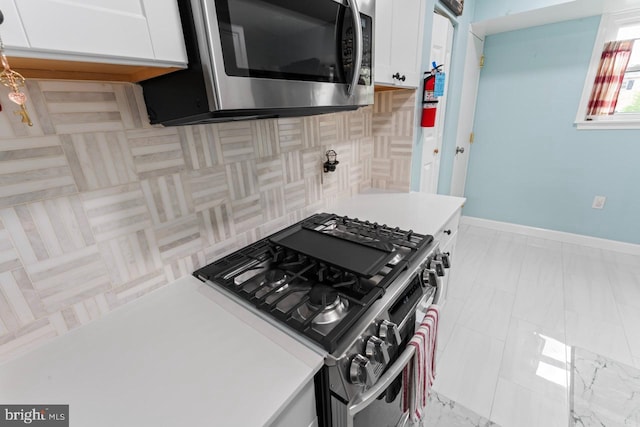 kitchen featuring light countertops, baseboards, stainless steel appliances, and white cabinetry